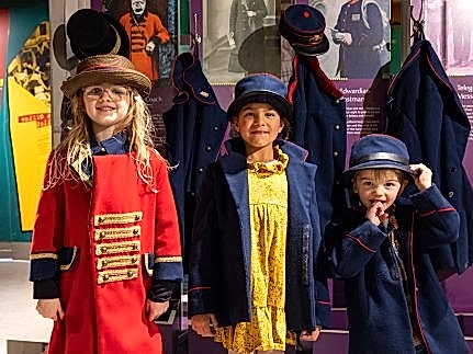 Photo of three children dressing up in postal uniforms.
