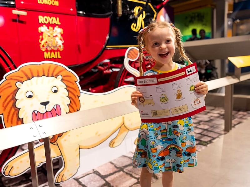Small white girl holding a Dear Zoo exhibition trail map
