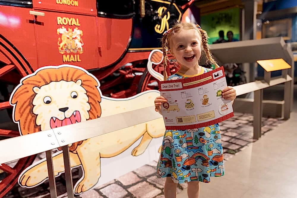 Small white girl holding a Dear Zoo exhibition trail map