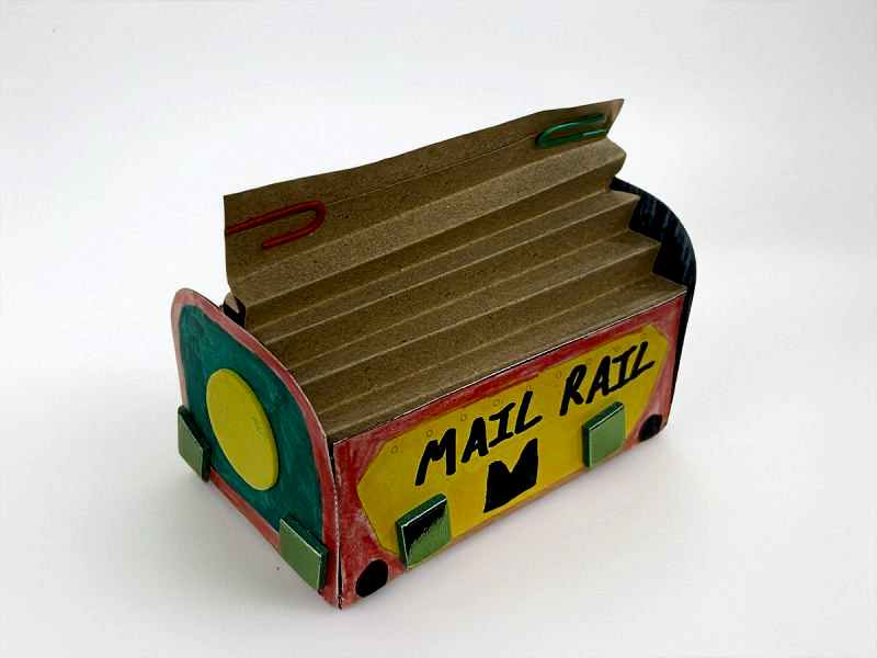 A colourful red, yellow and green paper model of a Mail Rail York trolley.