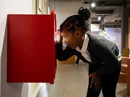 A child looking into a postbox in the exhibition space.