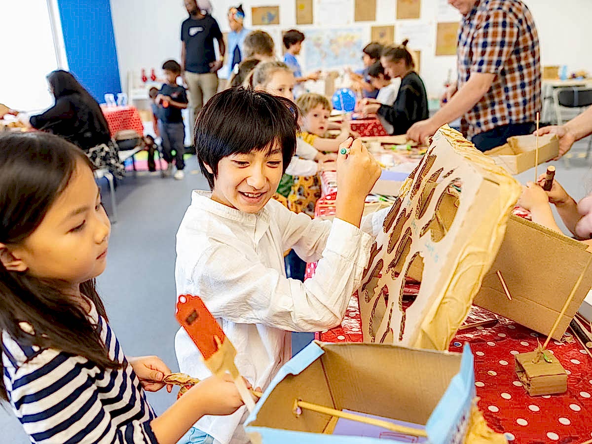 Children at an arts and crafts activity colouring with cardboard and paper.