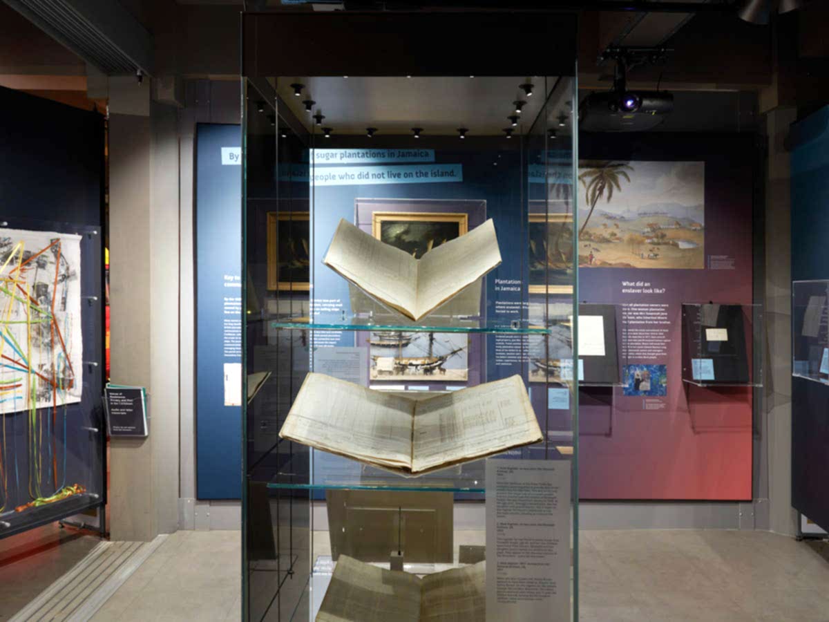 A glass exhibition case containing large books.