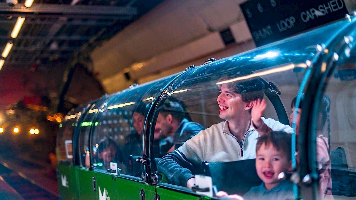 A family riding a miniature green train.