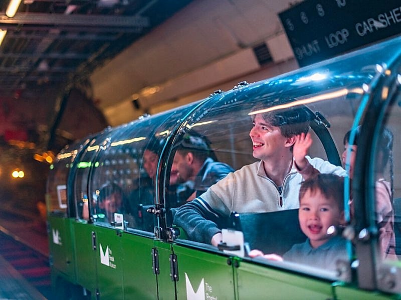 A family riding a miniature green train.