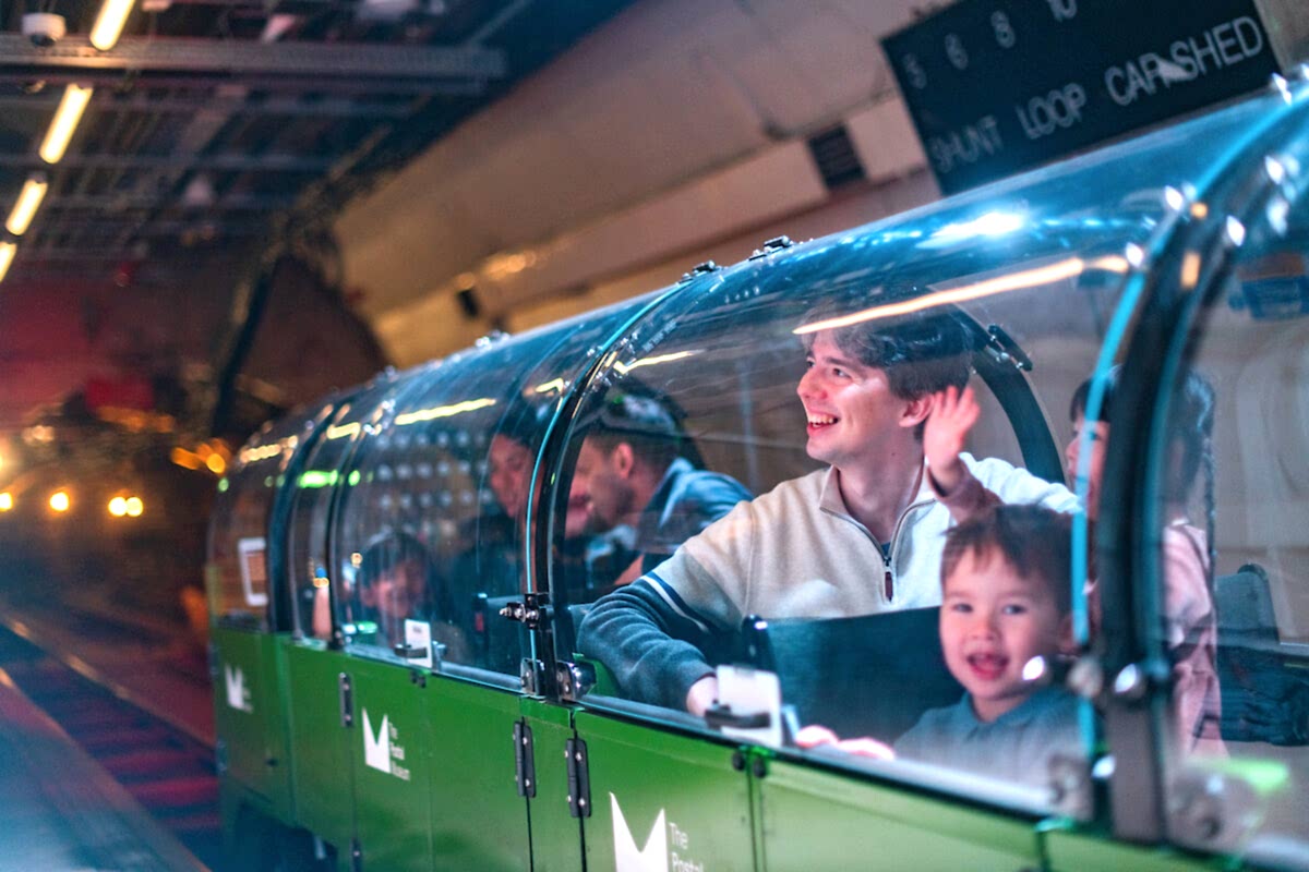 A family riding a miniature green train.