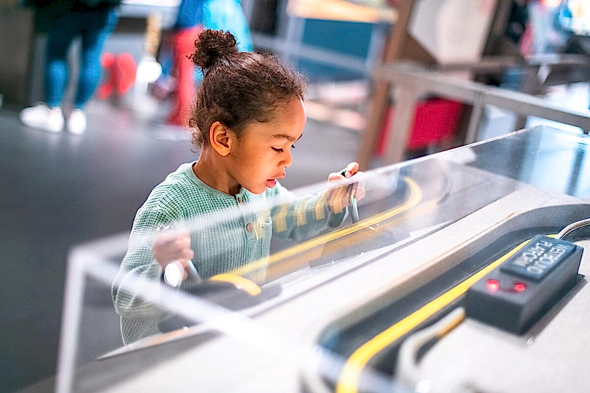 A child playing with an interactive museum exhibit.