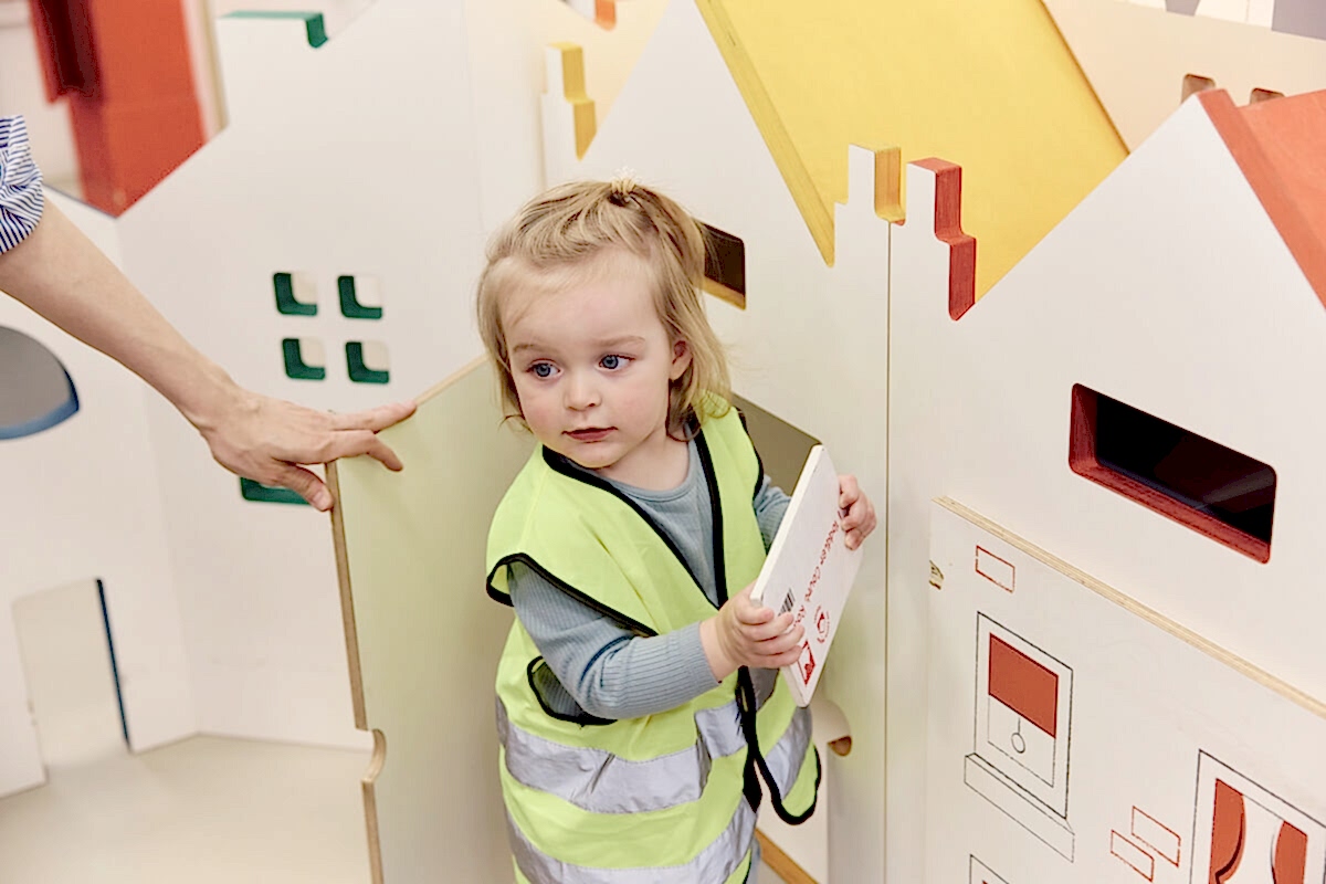 A child playing with a miniature door in a play space.